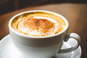 close up modern hot black coffee the cappuccino on wood background with coffee bubble foam pattern and texture in white cup looking and feel so delicious on glasses table in coffee shop.