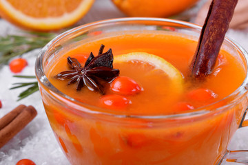 Fruit punch with sea buckthorn berries, citrus and spices in a glass cup in snow