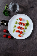 Three stuffed tomatoes on a white plate on grey background