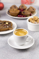 a cup of coffee, a slice of chocolate cake and muffins on the table