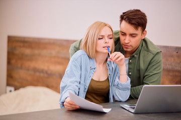 portrait of sad irritated disappointed analyzing of finance using modern laptop, discuss mortgage or purchase. blond female and handsome man wearing casual wear at home