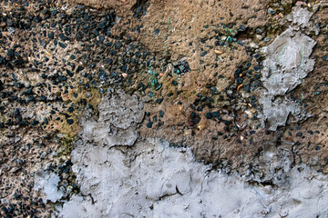 Rough concrete wall with black rocks and stucco