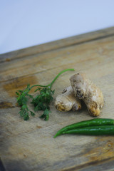 Fresh organic ginger with chilly and coriander leaves on wooden background.
