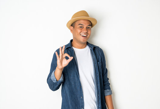 Asian men aged around 30 wearing hats and jeans showing ok sign.