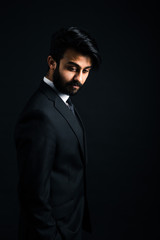 Obraz premium Portrait of a young handsome successful Indian in a classic black three-piece business suit on a dark background