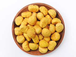 Top view of a pile of yellow peeled chestnuts on wooden plate isolated on white background. Food concept. Ingredient used for cook.