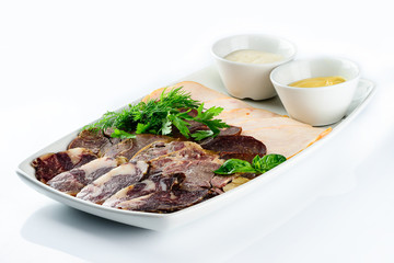 plate with a set of sausages and ham decorated with basil and sauce