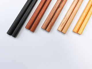 Top view of five color wooden chopsticks are arranged isolated on white background. Main tableware in East and Southeast Asia. Traditional culture and lifestyle concept. With copy space.