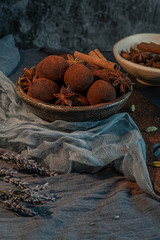 Craft chocolate truffles on plate with cocoa powder and anise, cinnamon, cardamom.