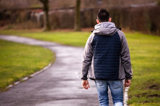 young man walking through neighborhood park
