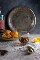 a glass of whiskey with steel balls for cooling, a plate with persimmon chocolate and a bottle