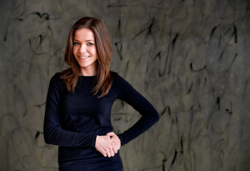 Photo of a pretty glamorous brunette girl in a black t-shirt with long hair on a gray alternative fashionable original background. Beauty concept, stylish portrait.