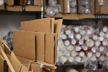 folded cardboard boxes in front of new unused paper cups in warehouse
