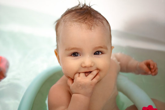 Cute newborn girl bathes in the bathroom