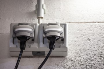industrial electrical outlets mounted on wall under flourescent lamp