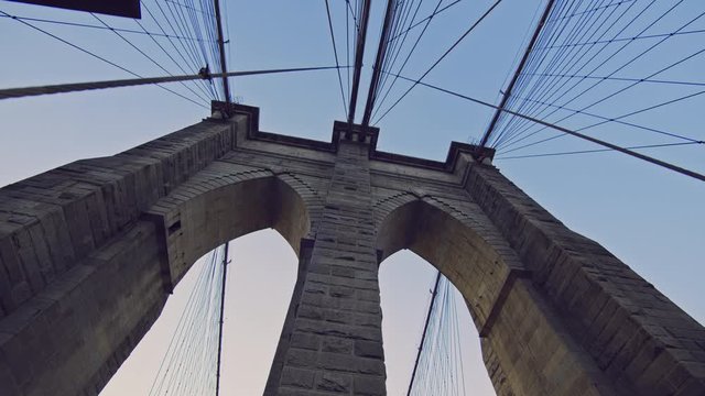 Low angle view on the iconic Brooklyn Bridge in NYC, a famous tourist destination and landmark, clear blue sky sunny day 