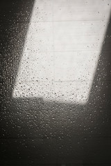 Light and shadow on shower wall covered with droplets of water