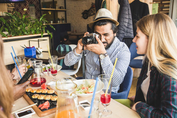 Group of young cheerful friends are sitting in a cafe, eating, drinking drinks. Friends take selfies and take pictures.
