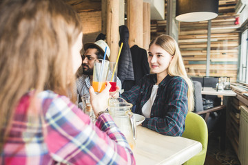 Meet young attractive people in the cafe. Friends chat, have fun, drink cocktails and eat