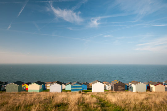 Colourful beach huts against a cloudy sky and facing the  sea.