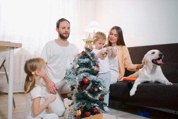 Happy caucasian family have new year's bustle at home, decorating new year tree with colorful...