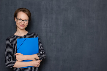 Portrait of cheerful young woman smiling and holding folder and pen