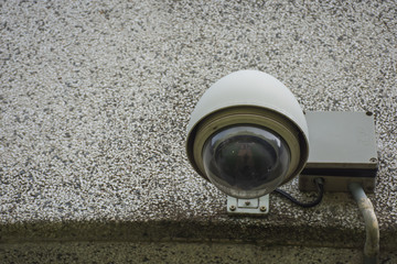 Large white CCTV on light beige stone wall of public buildings.