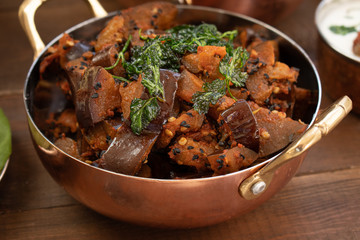Indian vegetarian eggplant curry served in copper bowl