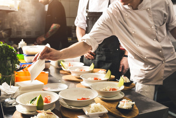 Professional chef cooking in the kitchen restaurant at the hotel, preparing dinner. A cook in an apron makes a salad of vegetables and pizza.
