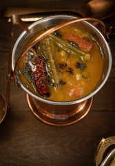 Spicy South Indian lentil, moringa and carrot stew served in copper serving pail