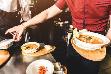 Professional chef cooking in the kitchen restaurant at the hotel, preparing dinner. A cook in an apron makes a salad of vegetables and pizza.