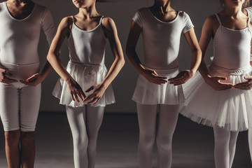 Fototapeta na wymiar little caucasian girls in white tutu skirts and pointe shoes dream of becoming great ballerinas, training, practicing classic ballet dance in studio, group of little caucasian graceful girls