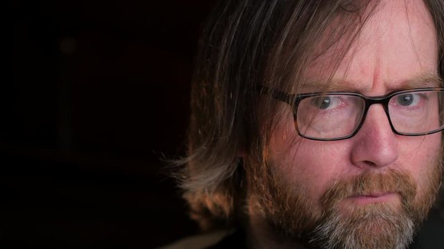 Bearded man changing his expression from doubting to being surprised, close up shot
