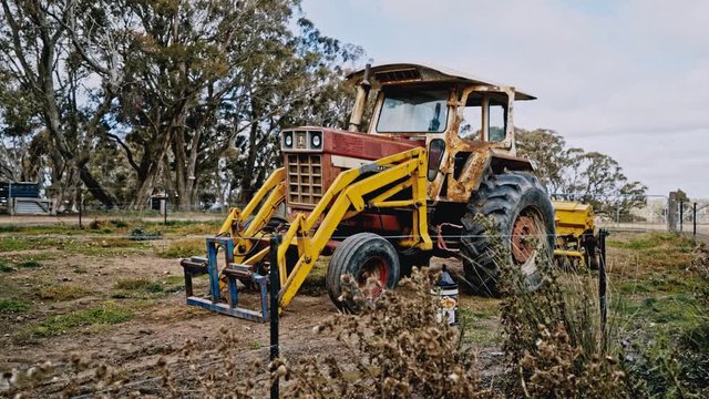 An unused and rusty tractor sits in the field of a farm