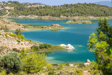 Scenic view at the Gadoura water reservoir on Rhodes island, Greece with blue and turquoise water and green landscape around the lake