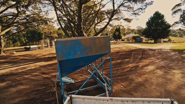 A farmer tows his large feeding bin with hsi pick up truck. POV shot
