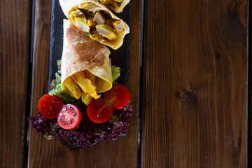 Tortilla with chicken and curry, baby tomatoes, served on a stone plate