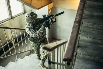 young soldier carrying out military service, in readiness at work, in landing, holding weapon