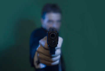 Man pointing handgun - dramatic action portrait of out of focus special agent or police officer aiming with gun to the camera in law enforcement and crime concept