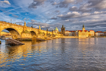 Beautifully illuminated Charles Bridge at sunset with surrounding buildings, Prague