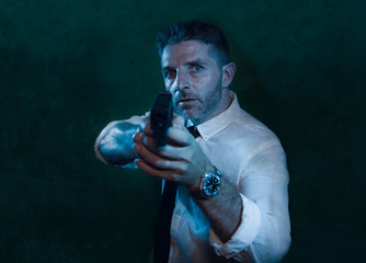 Man pointing handgun - dramatic action portrait of attractive special agent or police officer aiming with gun in white shirt and tie holding the weapon serious in law enforcement
