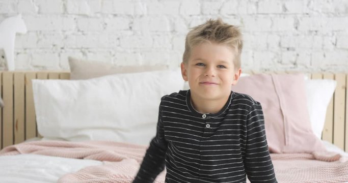 Gesture of greeting or farewell. Happy childhood of cute boy. Laughing caucasian child in modern interior. Poratrait of smiling little boy 5 ages looking at camera and waving hand. Happiness concept.
