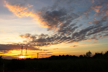 Mobile phone communication antenna tower with silhouette in sunset sky background