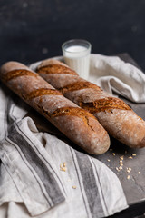 fresh buns and milk in a glass on a wooden board and a cotton towel