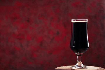 craft dark beer in a glass on a creative dark red background