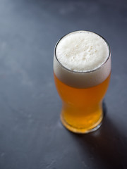 glass of craft unfiltered beer ale on a gray table close up