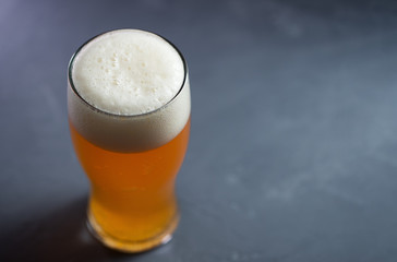 glass of craft unfiltered beer ale on a gray table close up