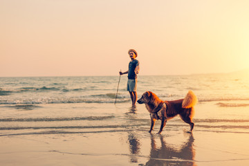 A man and a dog stand on the beach and sunset, sunrise.