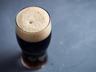 A glass of dark craft beer on a gray table