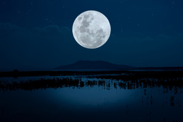 Bright moon over lake at night.